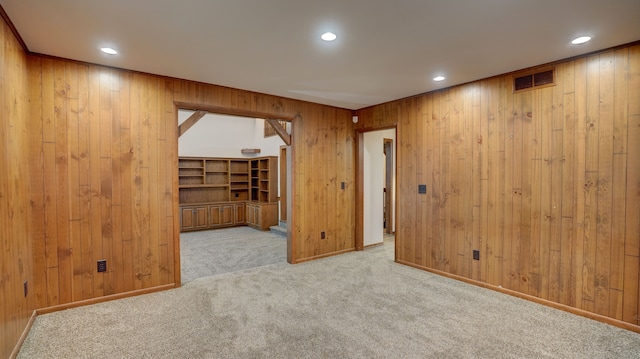 unfurnished room with wooden walls and light carpet