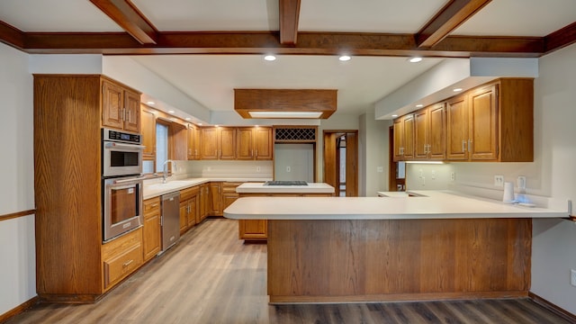 kitchen with kitchen peninsula, stainless steel appliances, light hardwood / wood-style floors, and sink