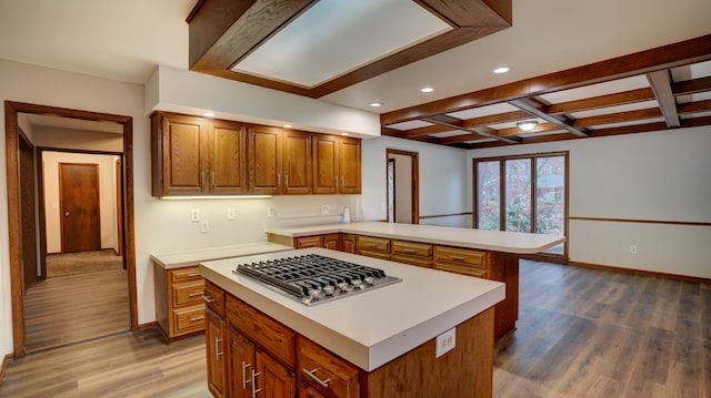 kitchen featuring coffered ceiling, stainless steel gas cooktop, dark hardwood / wood-style flooring, kitchen peninsula, and a kitchen island