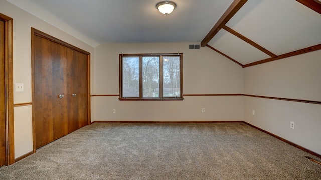 carpeted empty room with vaulted ceiling with beams