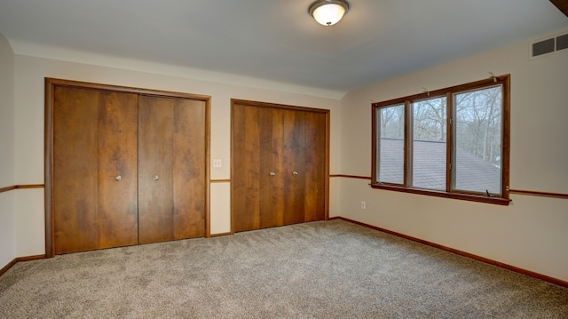 unfurnished bedroom featuring carpet flooring and two closets