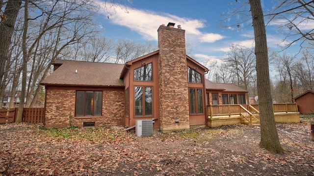 rear view of property with a sunroom, cooling unit, and a deck