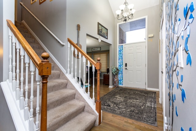 foyer entrance with hardwood / wood-style floors, a chandelier, and lofted ceiling