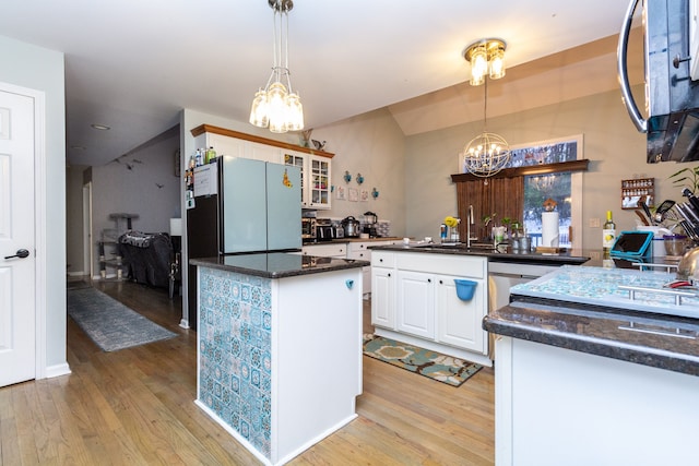 kitchen featuring decorative light fixtures, white cabinetry, sink, and light hardwood / wood-style flooring