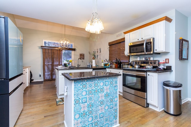 kitchen with an inviting chandelier, kitchen peninsula, light hardwood / wood-style floors, white cabinets, and appliances with stainless steel finishes