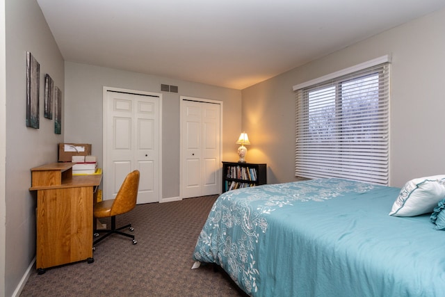 bedroom featuring multiple closets and dark carpet