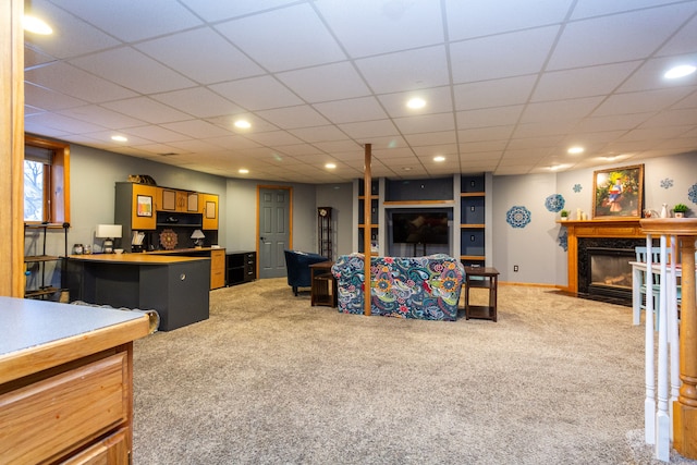 carpeted living room with a drop ceiling and a fireplace