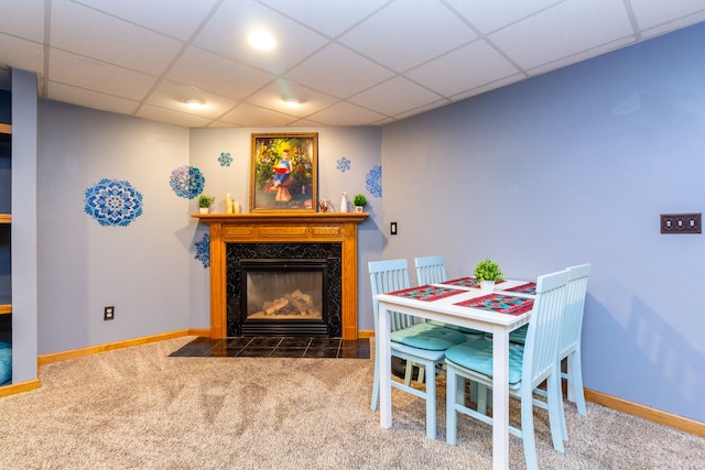 dining space with a fireplace, carpet, and a paneled ceiling