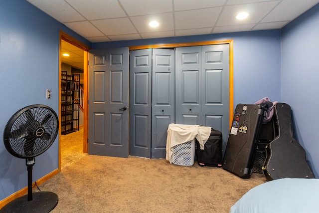 bedroom with a paneled ceiling, light colored carpet, and a closet