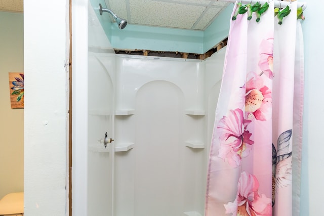 bathroom featuring a paneled ceiling and walk in shower