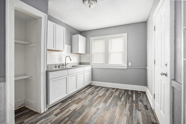 kitchen featuring dark hardwood / wood-style flooring, tasteful backsplash, white cabinetry, and sink