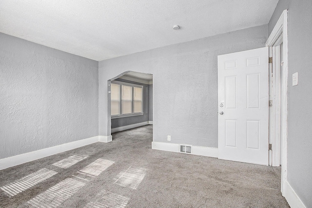 carpeted empty room with a textured ceiling