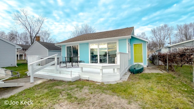 rear view of house with a wooden deck and a lawn