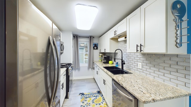 kitchen featuring light stone countertops, sink, white cabinets, and appliances with stainless steel finishes