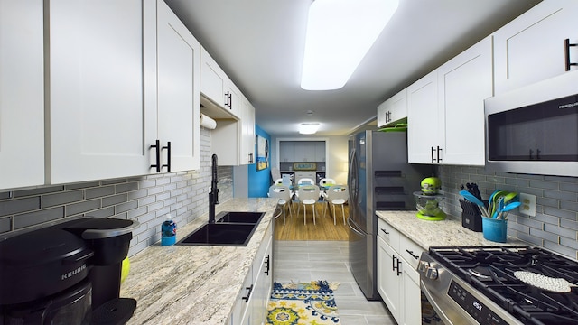 kitchen with white cabinets, stainless steel appliances, and light stone countertops