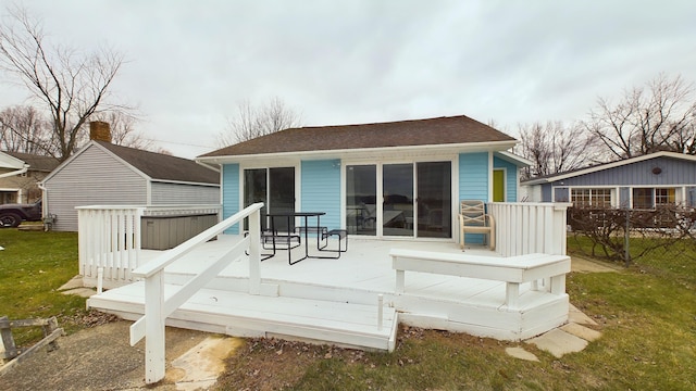 rear view of property featuring a deck and a lawn