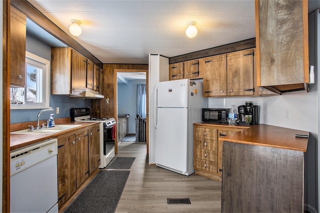 kitchen with a textured ceiling, light hardwood / wood-style floors, white appliances, and sink