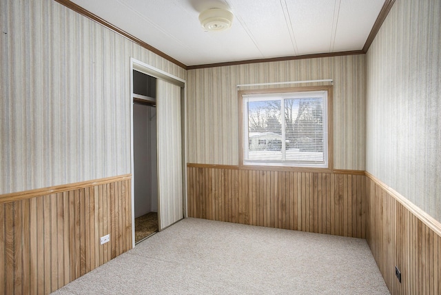 carpeted bedroom featuring wood walls, a closet, a textured ceiling, and ornamental molding