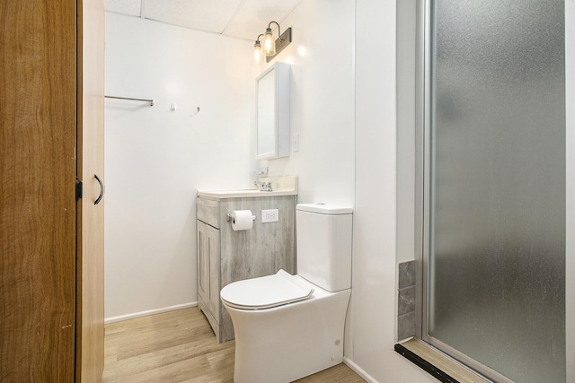 bathroom with wood-type flooring, vanity, toilet, and a shower with door