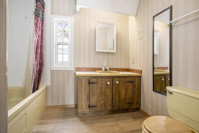 full bathroom with hardwood / wood-style flooring, vanity, toilet, and shower / tub combo