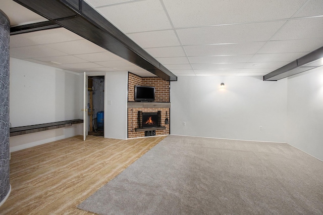 basement with a fireplace, hardwood / wood-style floors, and a drop ceiling