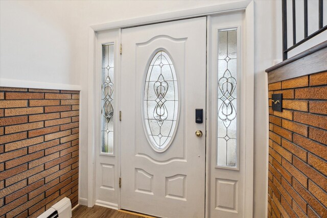 entryway with dark hardwood / wood-style floors, brick wall, and a baseboard heating unit