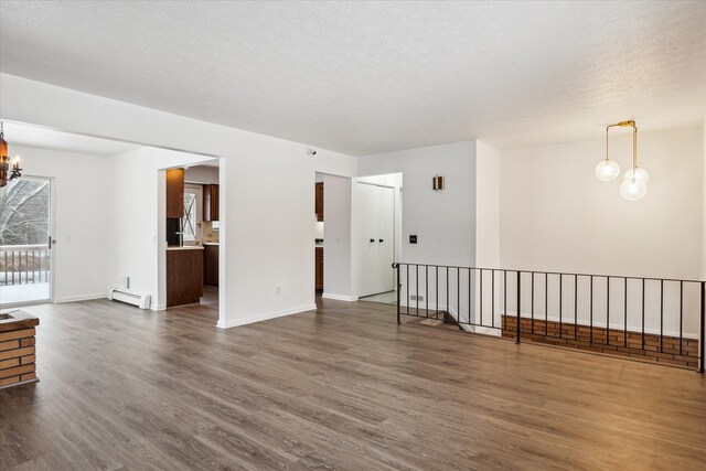 unfurnished room featuring a baseboard radiator, a textured ceiling, dark hardwood / wood-style floors, and a notable chandelier