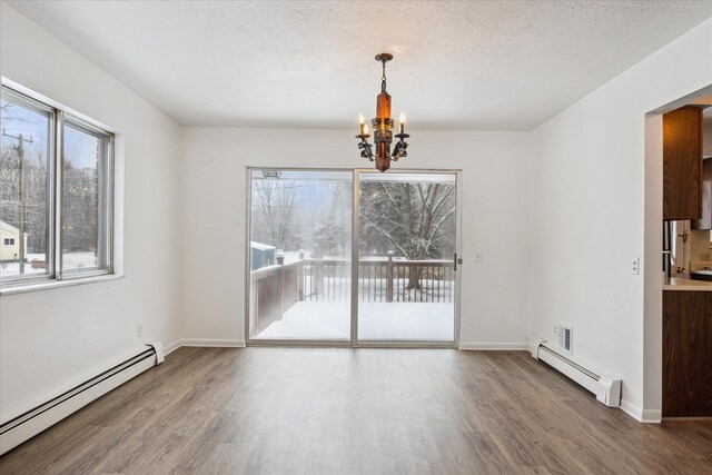 unfurnished dining area featuring wood-type flooring, a baseboard heating unit, and a chandelier