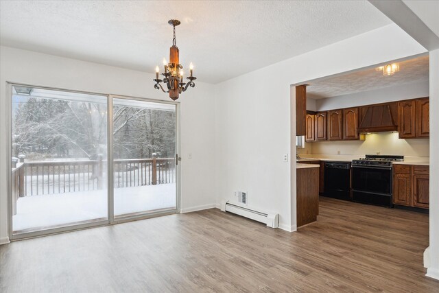 unfurnished dining area with hardwood / wood-style flooring, an inviting chandelier, a baseboard radiator, and a textured ceiling