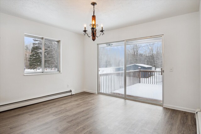 unfurnished room featuring wood-type flooring, baseboard heating, a chandelier, and a textured ceiling