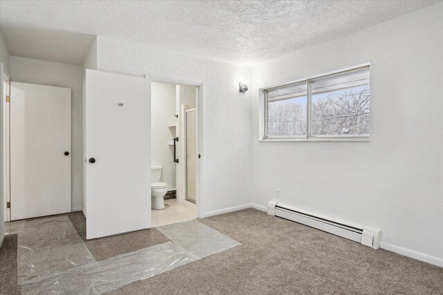 unfurnished room with a textured ceiling, baseboard heating, and light carpet