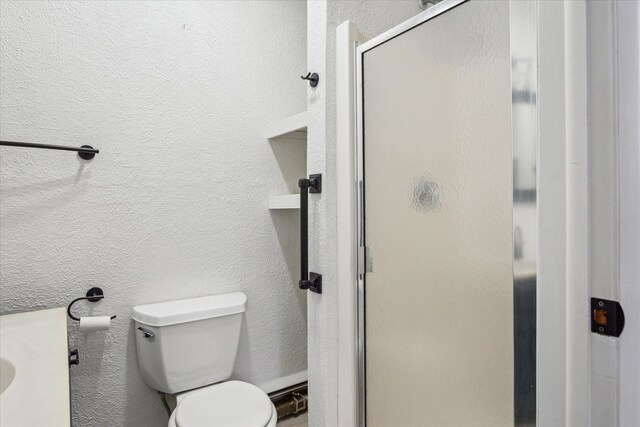 bathroom with toilet and a shower with shower door