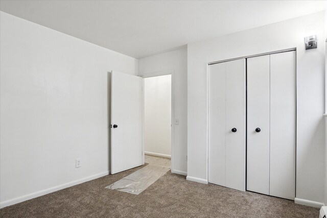 unfurnished bedroom featuring a closet and light carpet