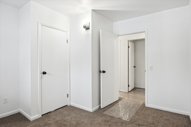 unfurnished bedroom with light colored carpet and a closet