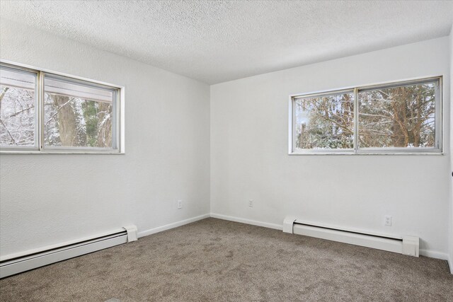 empty room featuring carpet floors, a baseboard radiator, and plenty of natural light