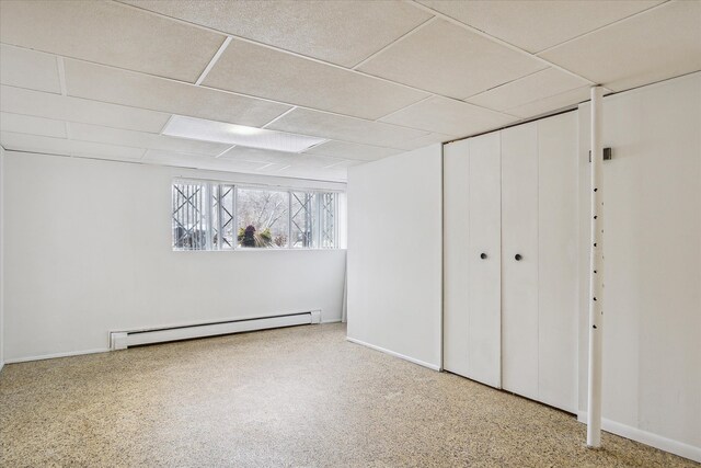 basement with a drop ceiling and a baseboard heating unit