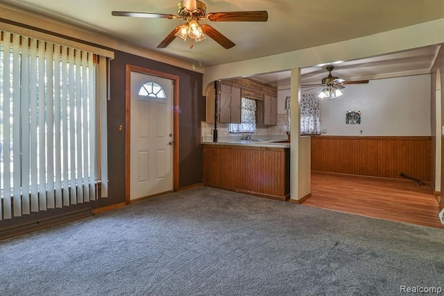 kitchen featuring ceiling fan, sink, backsplash, wood walls, and light hardwood / wood-style floors