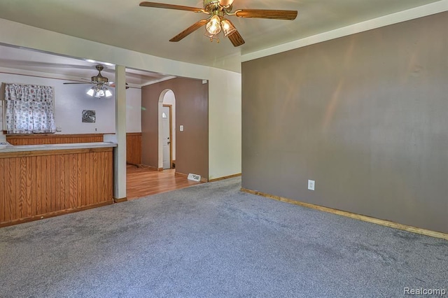 unfurnished living room with light carpet, crown molding, and ceiling fan