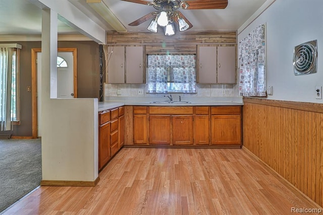 kitchen with plenty of natural light, light wood-type flooring, wooden walls, and tasteful backsplash