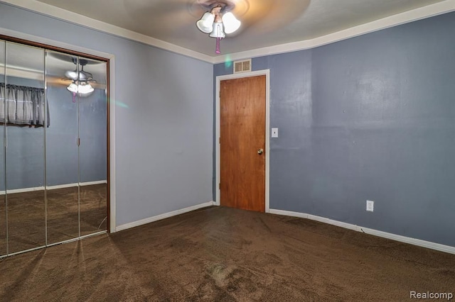 empty room with ceiling fan, ornamental molding, and dark colored carpet