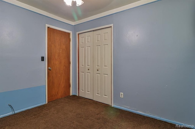 unfurnished bedroom with dark carpet, a closet, and ceiling fan