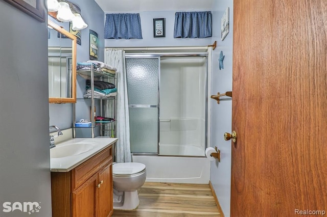 full bathroom featuring hardwood / wood-style flooring, vanity, toilet, and bath / shower combo with glass door