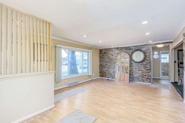 unfurnished living room with light hardwood / wood-style flooring, a healthy amount of sunlight, and ornamental molding