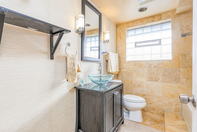 bathroom featuring vanity, toilet, and tile walls