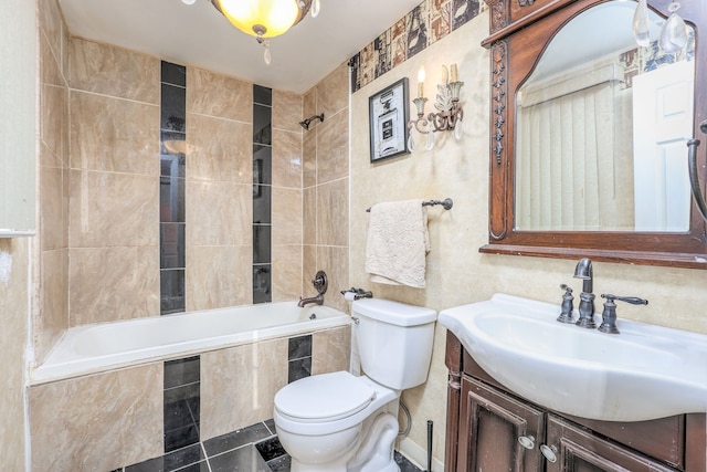 full bathroom with tile patterned floors, vanity, tiled shower / bath combo, tile walls, and toilet