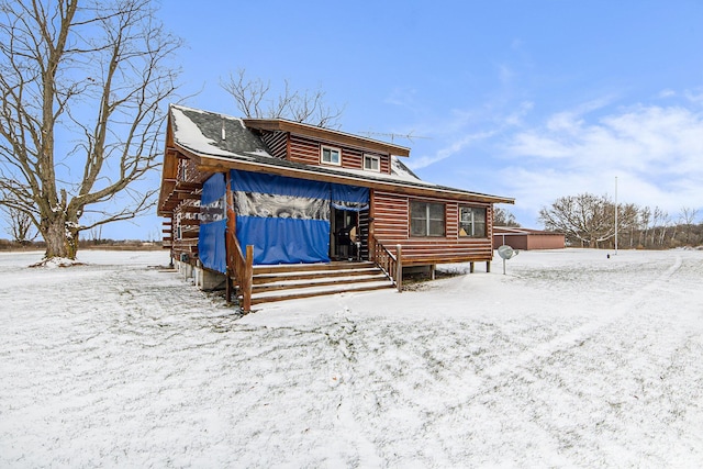 snow covered back of property with covered porch