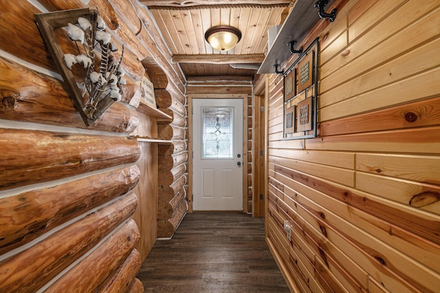 doorway to outside with log walls, dark hardwood / wood-style flooring, a barn door, and wooden ceiling