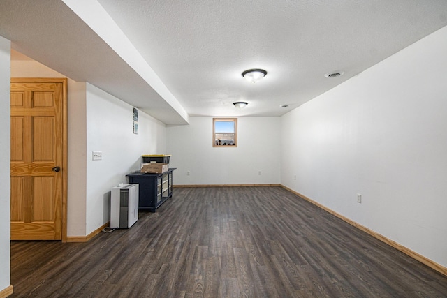 basement with a textured ceiling and dark hardwood / wood-style floors