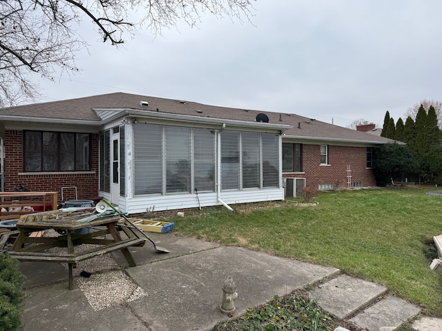 rear view of house with a yard, a patio area, a sunroom, and brick siding