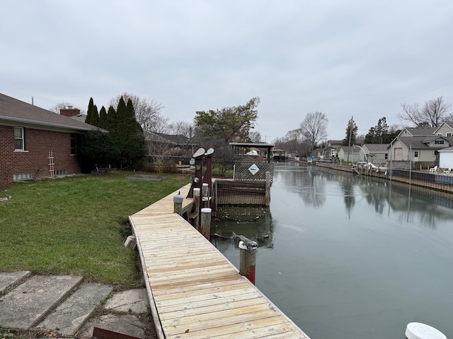 view of dock with a water view, a residential view, and a yard